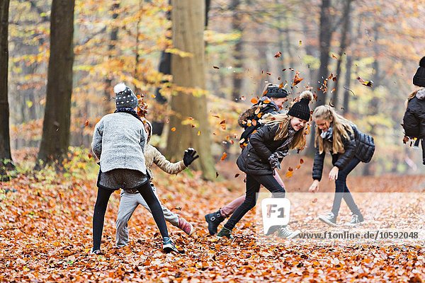 Girls playing with leaves in autumn forest