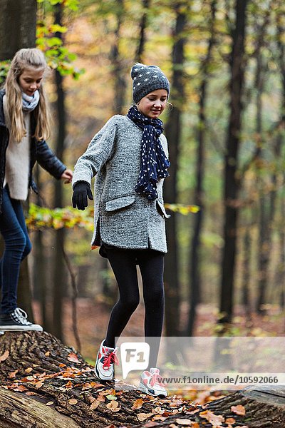 Mädchen auf Baumstamm im Herbstwald unterwegs