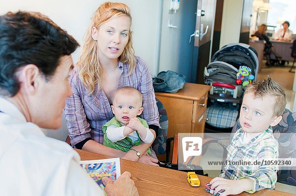 Mother sitting with two children  having discussion with doctor