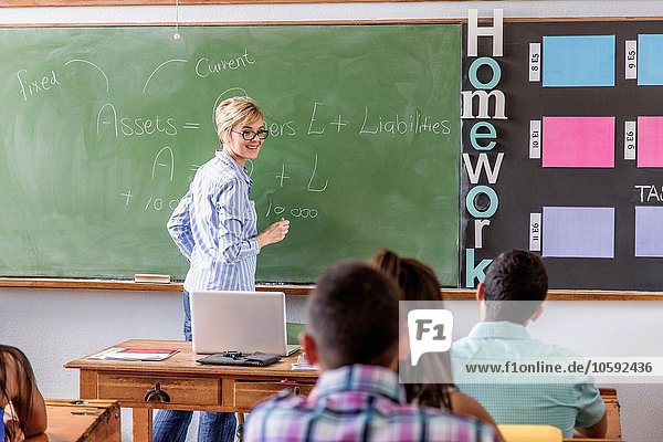 Female teacher addressing students in classroom