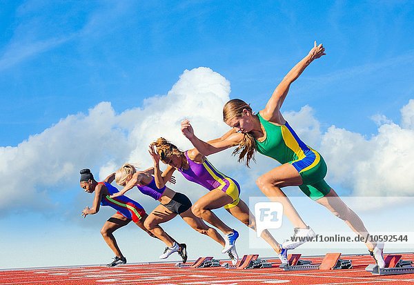 Four female athletes on athletics track  starting race