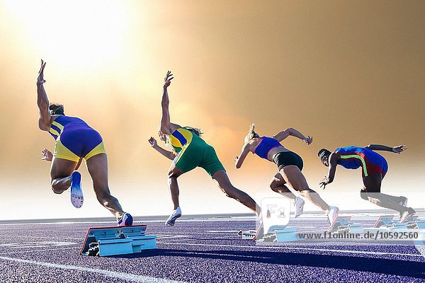 Vier Athletinnen auf der Leichtathletikbahn  Startblöcke verlassen  Rückansicht