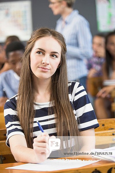 Porträt einer Schülerin  die am Schreibtisch im Klassenzimmer sitzt