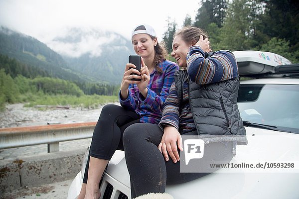 Hikers using smartphone on bonnet of vehicle  Lake Blanco  Washington  USA