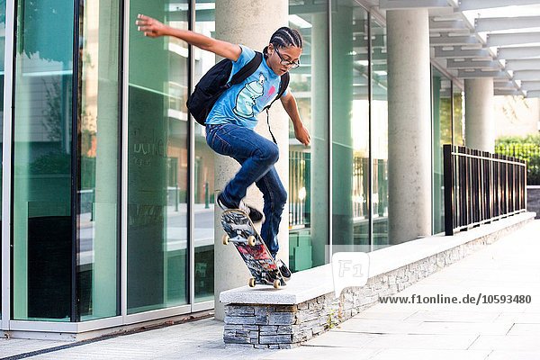 Junge macht Skateboard-Tricksprung an der Stadtmauer