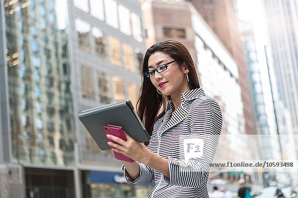 Businesswoman using digital tablet on street