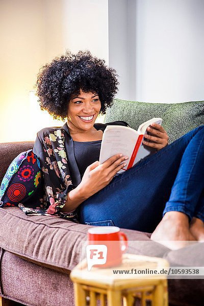 Mature woman relaxing on sofa reading book