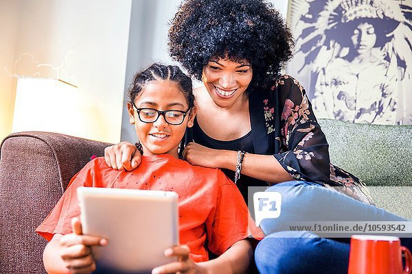 Mature woman and son reading digital tablet in living room