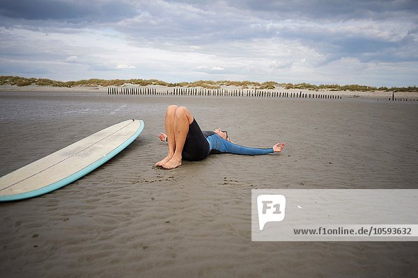 Seniorin entspannt auf Sand  Surfbrett neben ihr