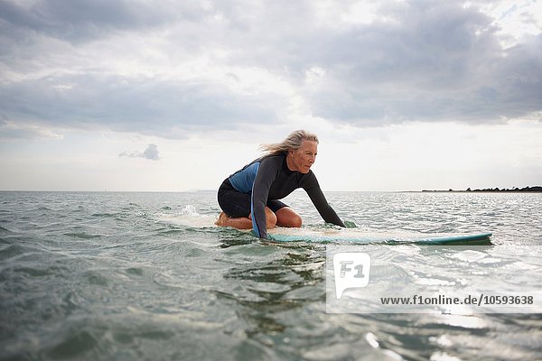 Senior woman on surfboard in sea  paddleboarding