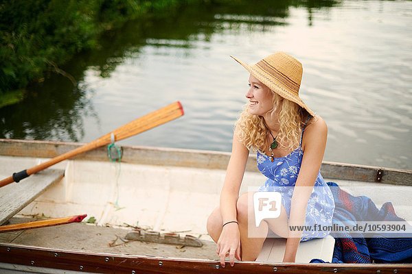 Porträt einer jungen Frau mit langen blonden Haaren im Ruderboot auf dem Fluss