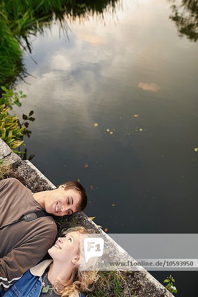 Draufsicht auf ein junges Paar das auf einer Flussbrücke liegt.