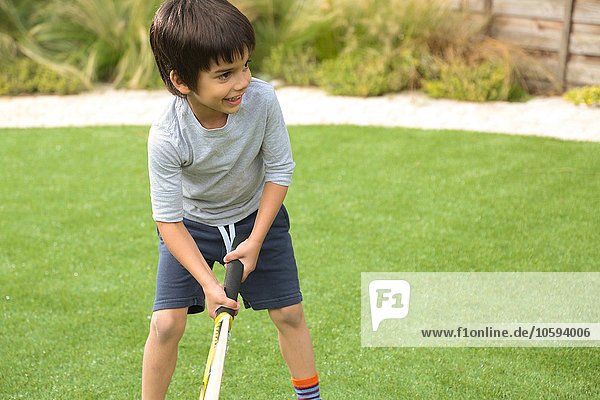 Front view of boy in garden playing cricket looking away smiling