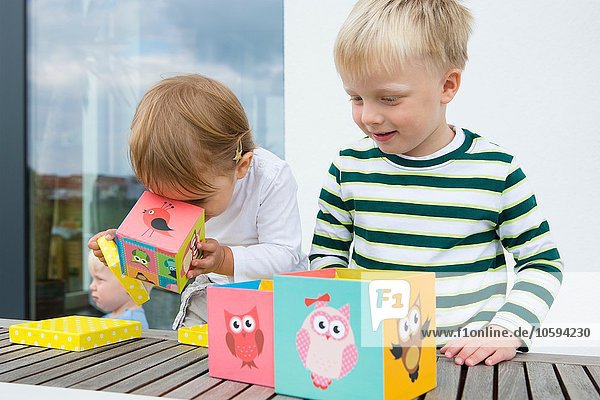 Boy and female toddler playing with owl building blocks on patio