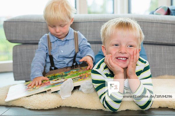 Männliches Kleinkind liest Kinderbuch auf dem Wohnzimmerboden