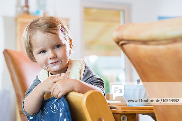 Portrait of female toddler leaning on dining room chair