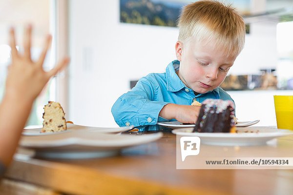 Male toddler eating cake at tea table