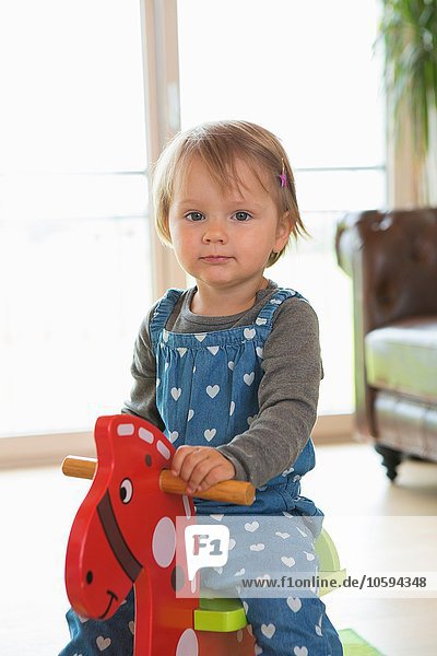 Portrait of female toddler playing on rocking horse