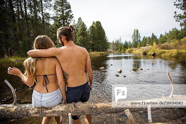 Rückansicht des jungen Paares auf einem umgestürzten Baum im Fluss  Lake Tahoe  Nevada  USA