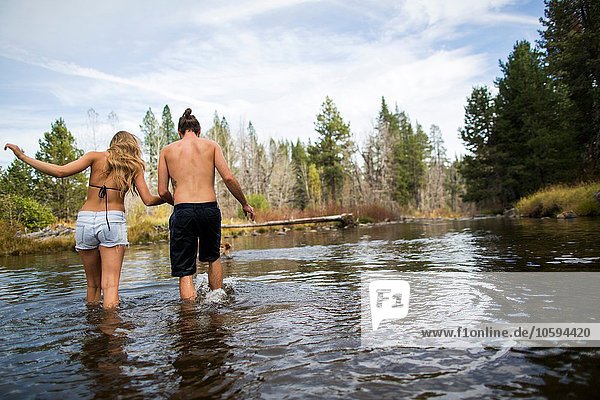 Rear view of young couple crossing river  Lake Tahoe  Nevada  USA