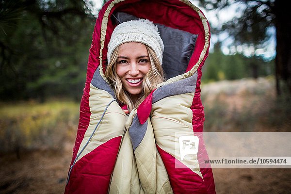 Portrait of young woman wearing knit hat wrapped in sleeping bag  Lake Tahoe  Nevada  USA
