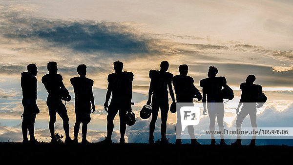 Silhouette einer Gruppe junger amerikanischer Fußballspieler  die in einer Reihe stehen.
