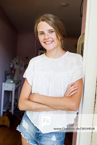 Portrait of pretty teenage girl leaning against doorway