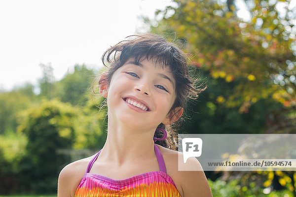 Porträt eines Mädchens mit farbenfrohem Neckholder-Top  das lächelnd auf die Kamera blickt.