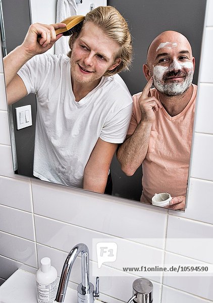 Badezimmer Spiegelbild des männlichen Paares beim Rasieren und Bürsten der Haare