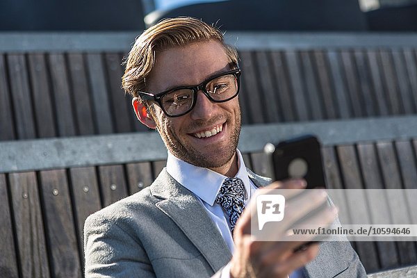Junger Geschäftsmann liest Smartphone-Text in der Stadt
