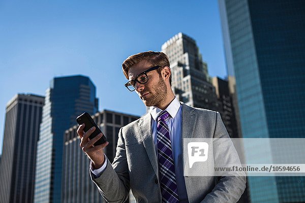 Jungunternehmer vor dem Bürogebäude beim Lesen von Smartphone-Texten New York USA