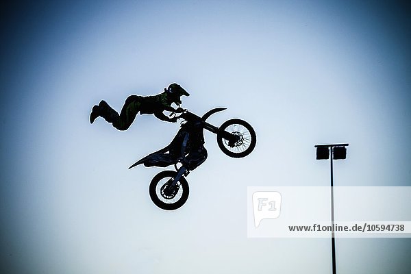 Man performing extreme stunt with motorcycle in mid air