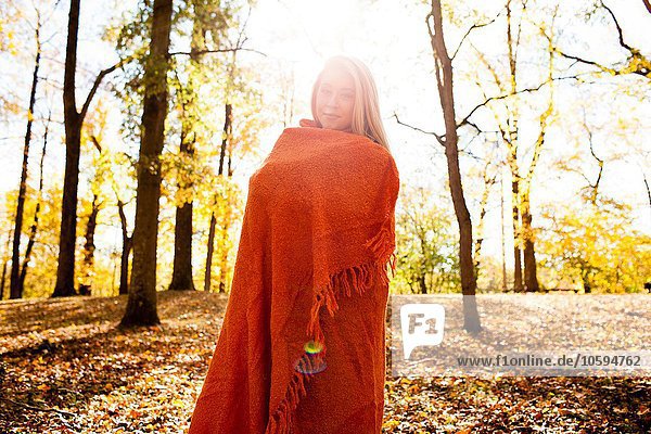 Porträt einer jungen Frau im Herbstwald in Decke gehüllt