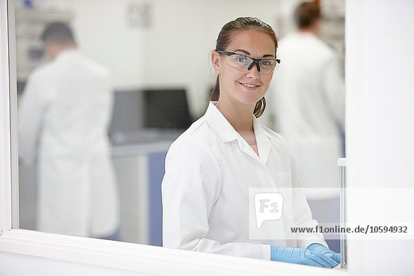 Scientist smiling in laboratory  colleagues working in background