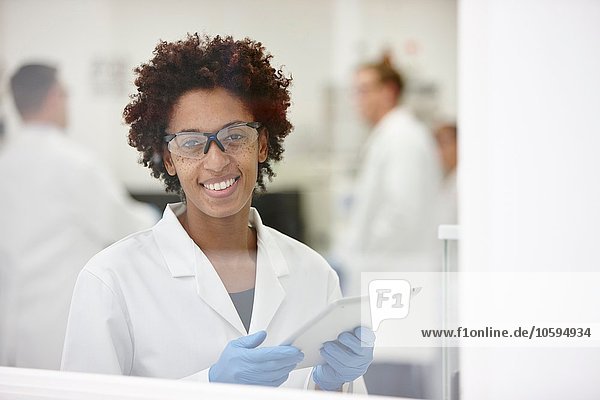 Scientist smiling in laboratory  colleagues working in background