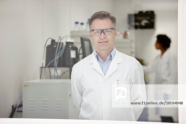 Scientist smiling in laboratory  colleague working in background