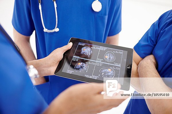 Doctors looking at scans on digital tablet