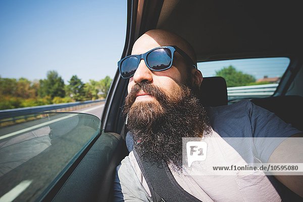 Bärtiger Mann mit Blick aus dem Autofenster auf der Autobahn  Garda  Italien