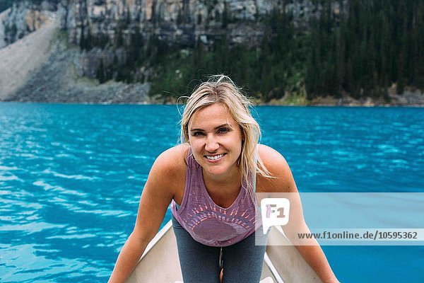 Porträt einer erwachsenen Frau im Kanu auf dem Moraine Lake  Blick auf die Kamera lächelnd  Banff National Park  Alberta Canada