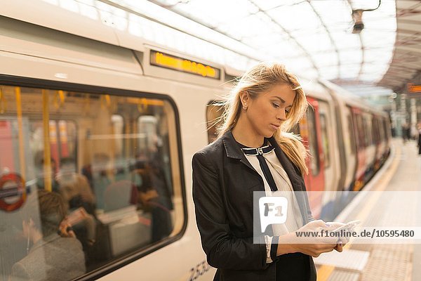 Geschäftsfrau SMS auf dem Bahnsteig  U-Bahnhof  London  UK