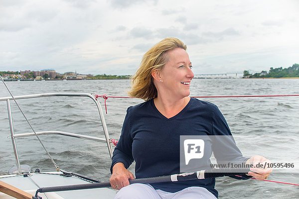 Mature woman streering sailboat looking away smiling