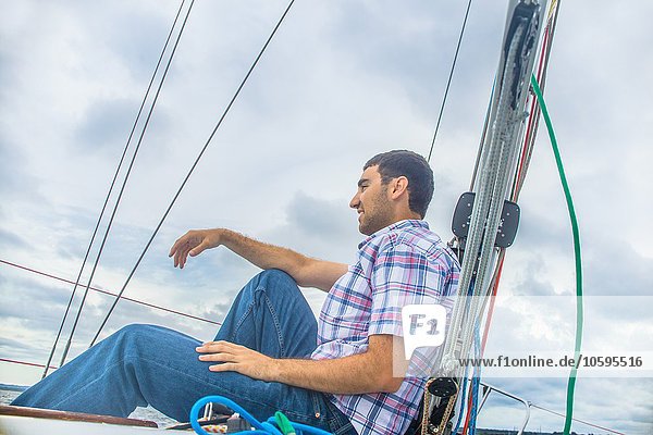 Low angle side view of young man on sailboat looking away smiling