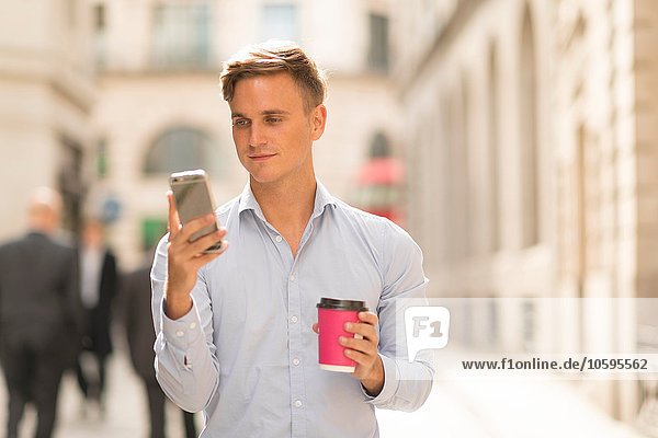 Mann mit Kaffee zum Mitnehmen per Smartphone