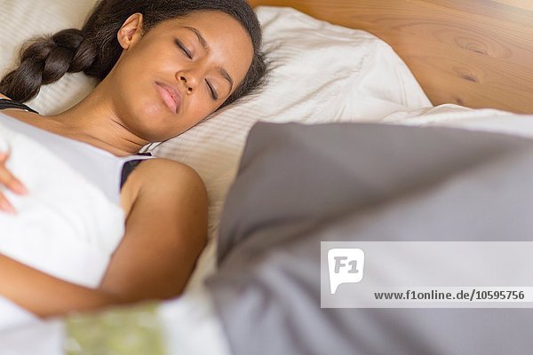 High angle view of young woman lying on back in bed eyes closed sleeping
