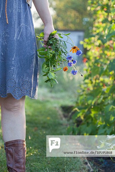 Reife Frau im Garten stehend  mit Wildblumen  Mittelteil