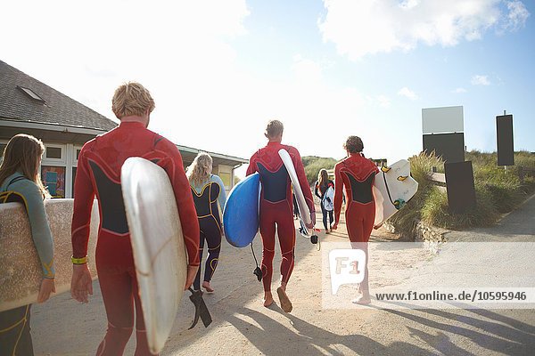 Gruppe von Surfern  die mit Surfbrettern in Richtung Strand gehen
