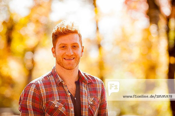 Sunlit portrait of red haired young man in forest