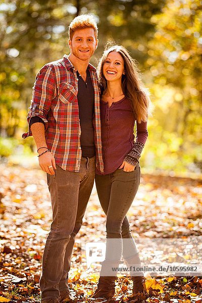 Sunlit portrait of young couple in autumn forest