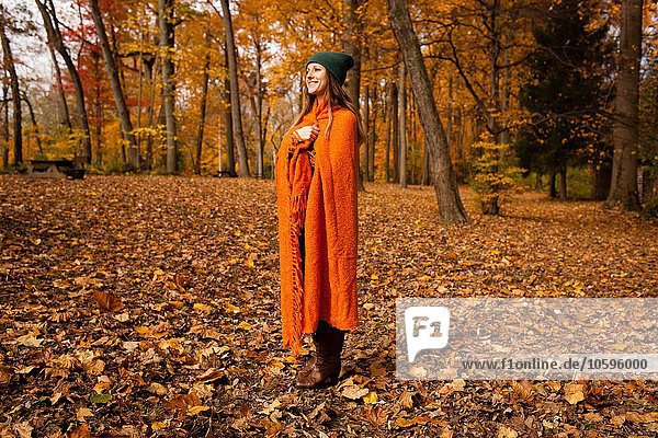 Junge Frau in orangefarbene Decke gewickelt im Wald