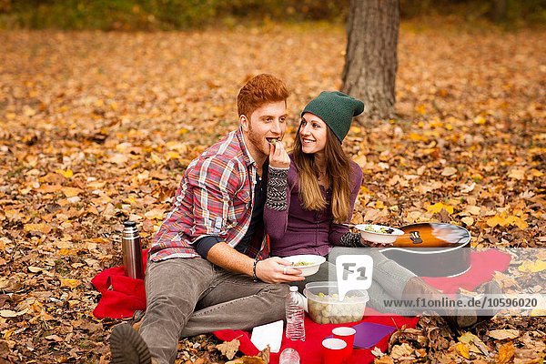 Young couple having picnic in autumn forest